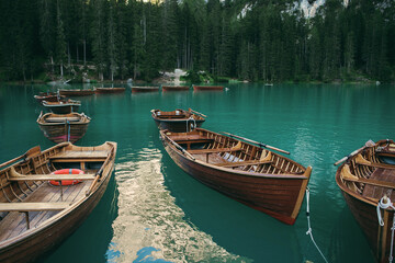 Fototapeta na wymiar wooden rowing boats on the river or lake in mountains with trees and cliff in the background