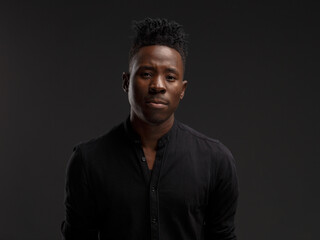 Fototapeta premium portrait of an African young man in a black shirt on a black background