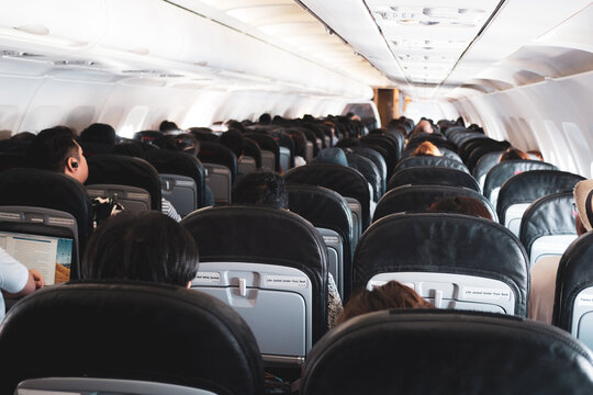 Interior of a plane with passengers on their seats .