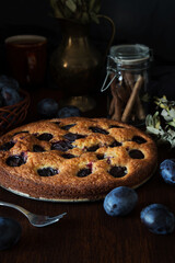 Dark photography of cake with cinnamon and plums