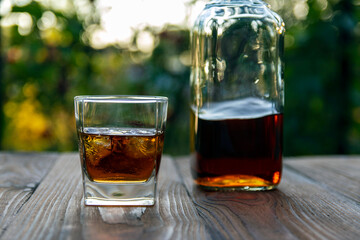 Fragrant whiskey, on an old garden table in the evening in the garden of a country house. Selective focus.