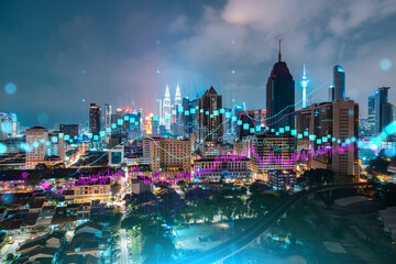 FOREX graph hologram, aerial night panoramic cityscape of Kuala Lumpur. KL is the developed location for stock market researchers in Malaysia, Asia. The concept of fundamental analysis.