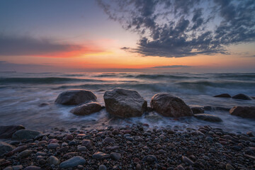 rocky seashore, colorful sunset on the background, long exposure