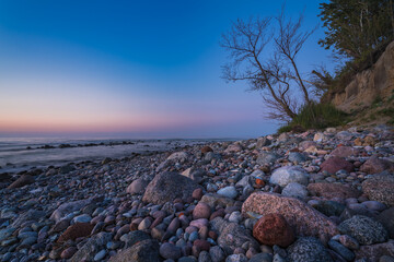rocky seashore, colorful sunset on the background, long exposure