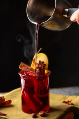 Mulled wine pouring into the glass on rustic background. warmer beverage  for cold day concept