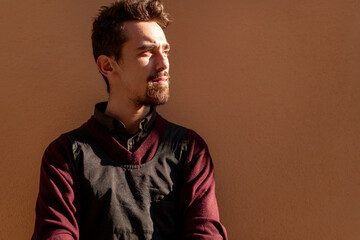 Confident bearded man in black apron looking away