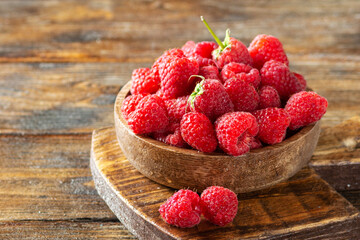Raspberries in a wooden bowl on a brown wooden table. Raspberry berry close-up. Fresh raspberries in a plate. Space for text. Healthy diet