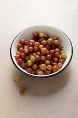 Red gooseberries in white enamel bowl