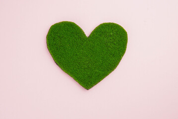 Earth day, ecology concept and environmental preservation. Green heart from grass on pink background. Love nature and save the planet and world.