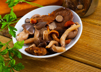 Fototapeta premium Assorted pickled mushrooms with onions and parsley closeup