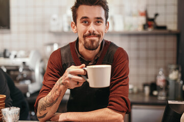 Cheerful barista with cup of coffee