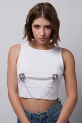 Young brown-haired lady is wearing steel nipple clips connected with a chain over her clothes. The...
