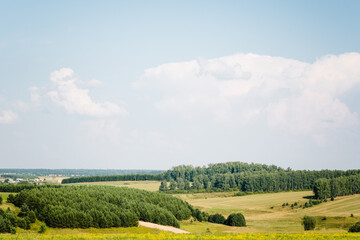 Beautiful summer rural landscape: fields, forests and blue sky. Tranquil landscape, green hills in summer. Concept about travel, tourism or study.