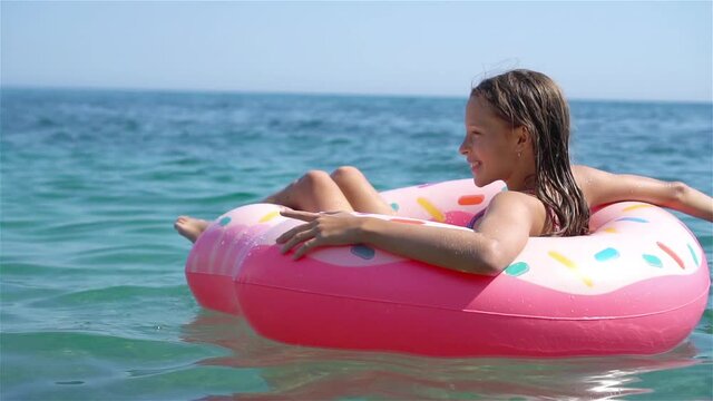 Adorable girl on inflatable air mattress in the sea