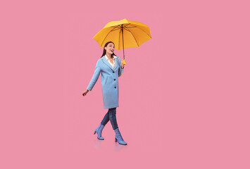 Portrait of excited young woman walking with umbrella