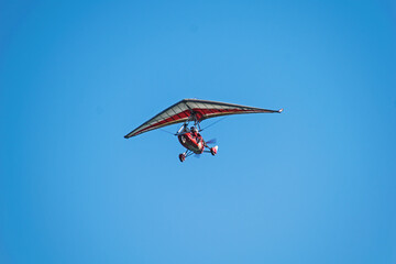 Hang glider with engine in flight. Pilot and a passenger. Tandem flight.