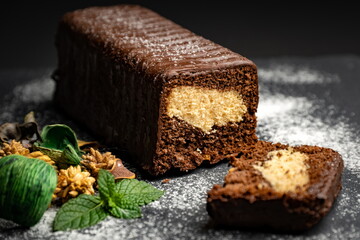 Chocolate cake on black background, icing sugar and decorative herbs