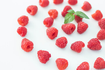 
Raspberries on a white plate and with mint in the middle.