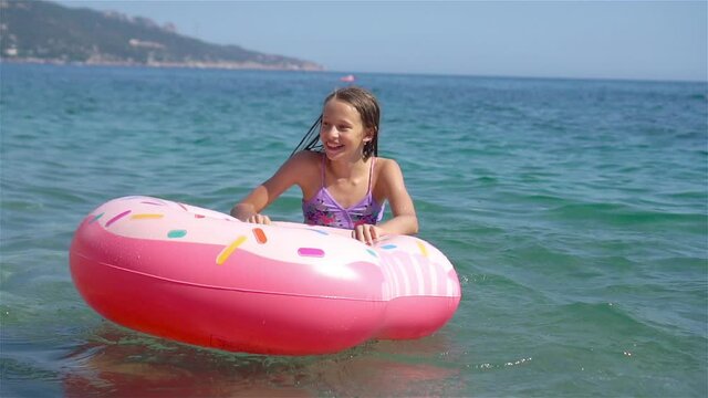 Adorable girl on inflatable air mattress in the sea