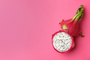 Halves of delicious ripe dragon fruit (pitahaya) on pink background, top view. Space for text