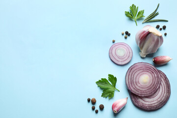 Flat lay composition with onion and spices on light blue background. Space for text