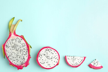 Delicious cut dragon fruit (pitahaya) on light blue background, flat lay. Space for text