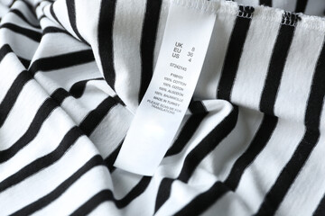 Clothing label with size and content information on striped garment, closeup