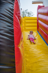 Cute blonde girl riding an inflatable slide.