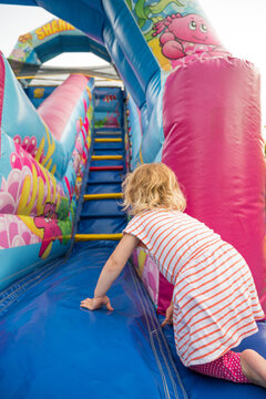 Cute blonde girl climbing on inflatable castle.