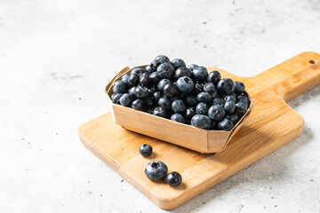 Blueberries in a wooden box on a light background. Fresh blueberries in a box