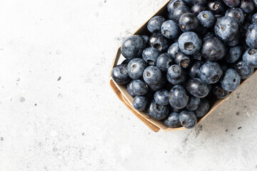 Blueberries in a wooden box on a light background. Fresh blueberries in a box. Top view with space for text