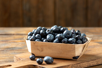 Blueberries in a wooden box on a brown wooden table. Fresh blueberries in a box. Space for text