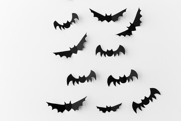 halloween, decoration and scary concept - flock of black paper bats flying over white background