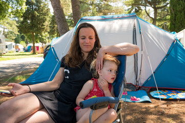 Mother sitting on a chair in camping resort with her daughter.