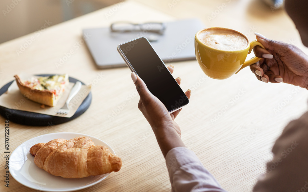 Poster unrecognizable black woman using smartphone while having breakfast with coffee at cafe, space for de