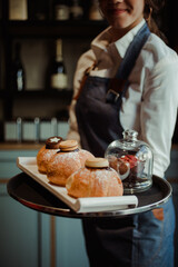 Cameriera che sorregge un vassoio con muffin e cornetti farciti