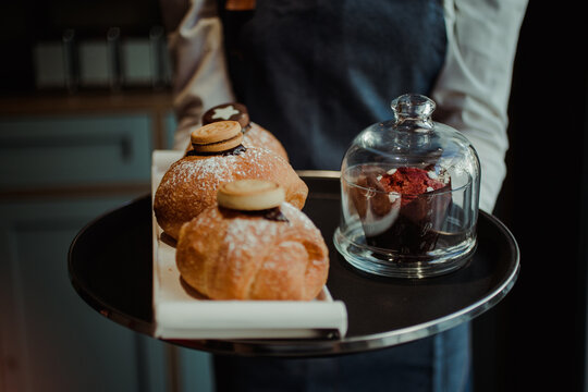 Cameriera che sorregge un vassoio con muffin e cornetti farciti