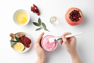 Woman making natural mask with pomegranate extract on white background, top view