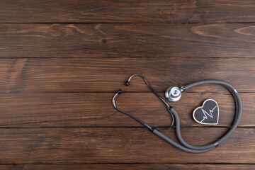 Workplace of a doctor. Stethoscope and little heart on wooden desk background