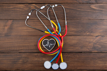 Workplace of a doctor. Colorful Stethoscopes and little heart on wooden desk background -...