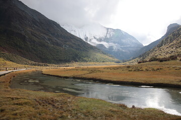 View of the sacred Mount Jampayang (Chinese: Yangmaiyong) with  Chonggu meadow and river of Yading Nature Reserve at Shangri-La region during Autumn in Daocheng county, southwest of Sichuan Province, 