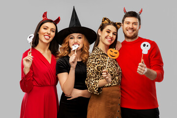 friendship, holiday and photo booth concept - group of happy smiling friends in halloween costumes...