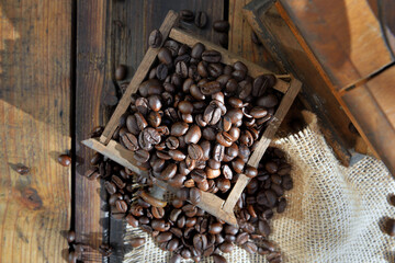 top view on a drawer of a coffee grinder filled with grain on rustic wooden background
