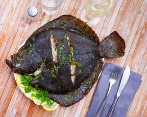 Appetizing roasted brill with lemon slices and herbs. Seafood delicacy..