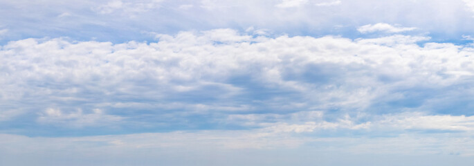Panorama of a cloudy sky, thick white clouds lined up