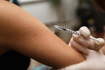 Pediatr vaccinating a little girl in her arm.
