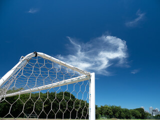Fototapeta premium 真夏の青空と土のサッカーコートの風景