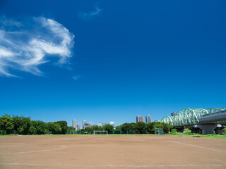 Fototapeta premium 真夏の青空と土のサッカーコートの風景