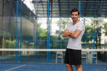 Happy young handsome Hispanic man at the padel court