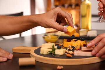 Obraz na płótnie Canvas Couple with different types of delicious cheeses at table indoors, closeup